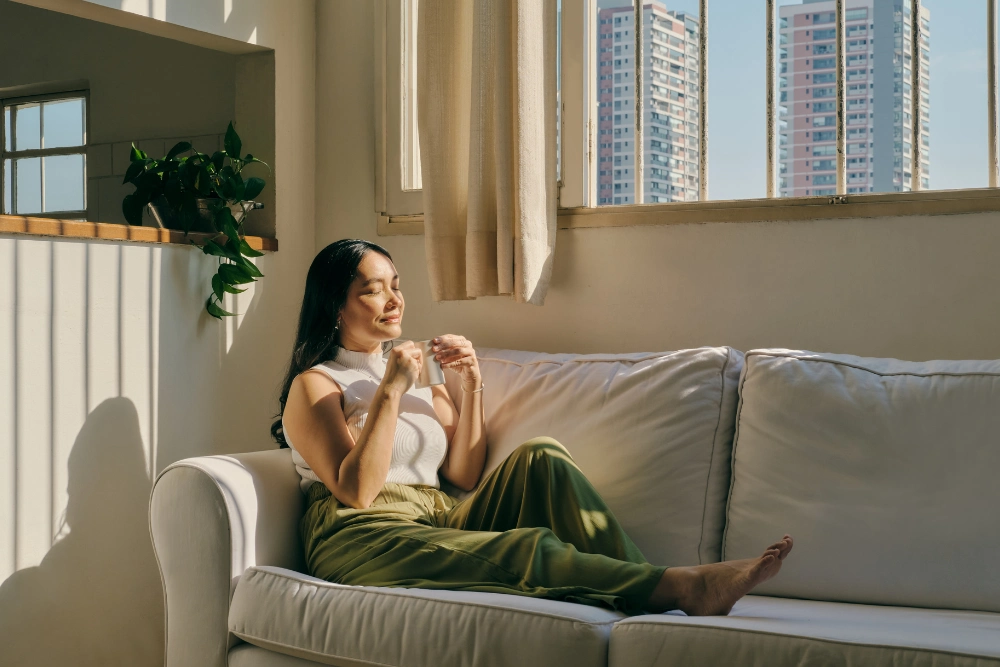 A woman happily sitting on her couch.